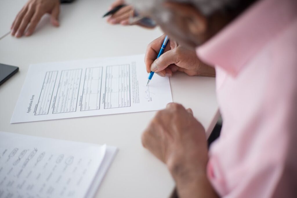 Elderly person signing legal documents with assistance